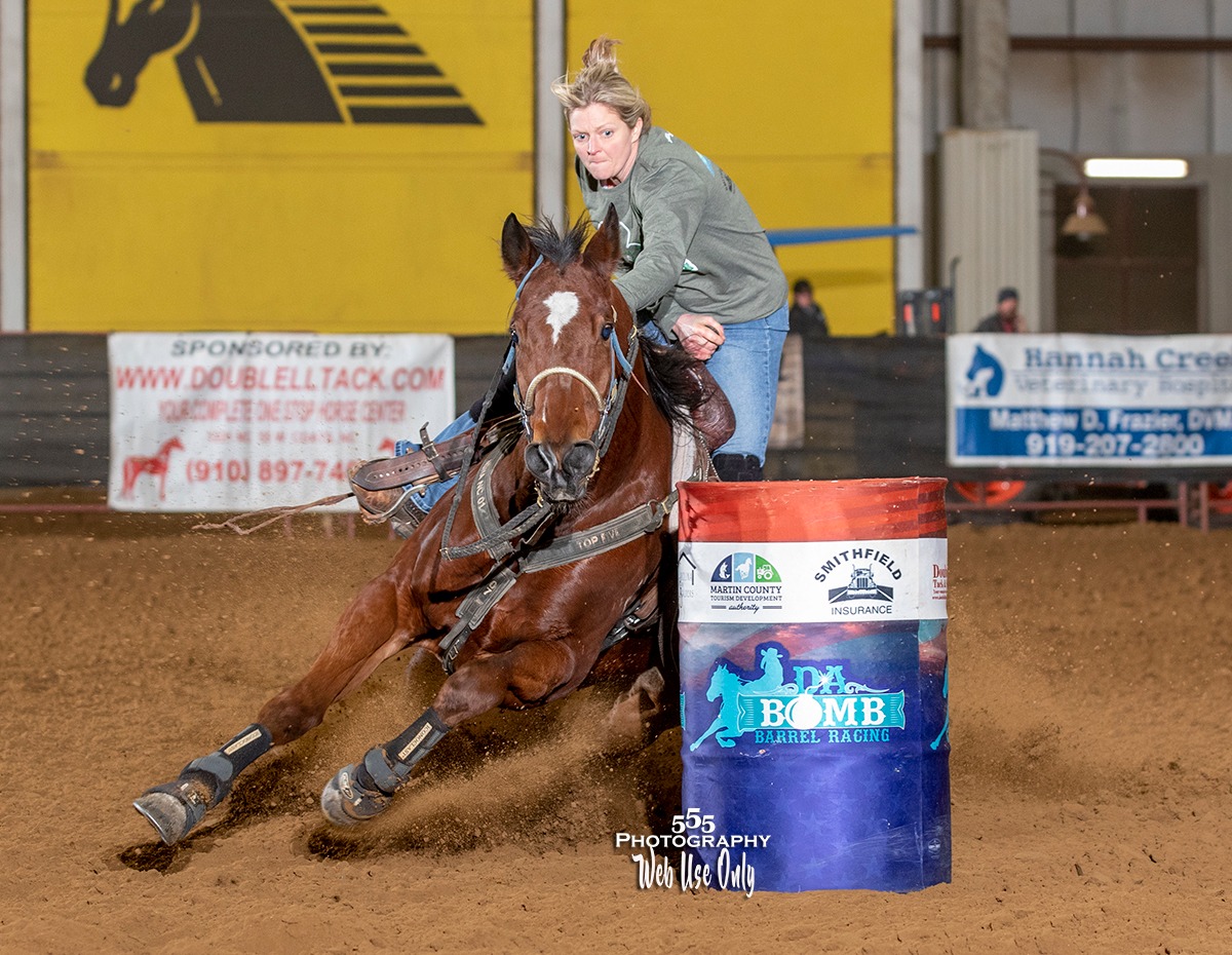 Barrel racing rider turning a barrel at speed during an indoor equine event